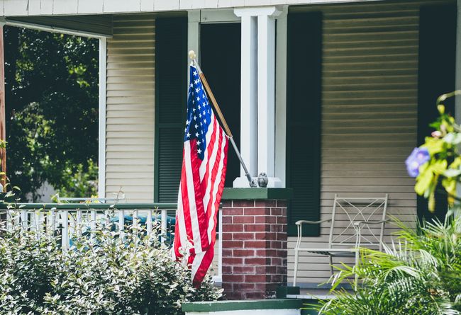 Yellow panel home with the US flag hanging in front of it