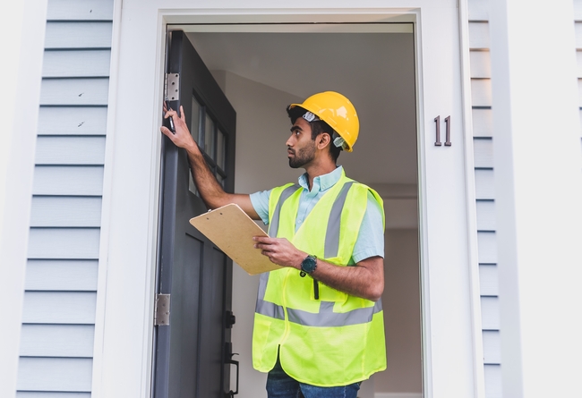 contractor inspecting a front door frame; can you sell a house with a violation