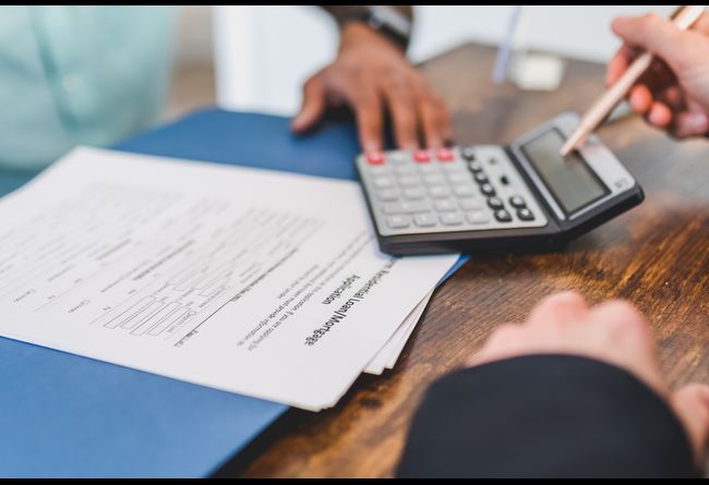 signing contract of a home with a calculator next to it