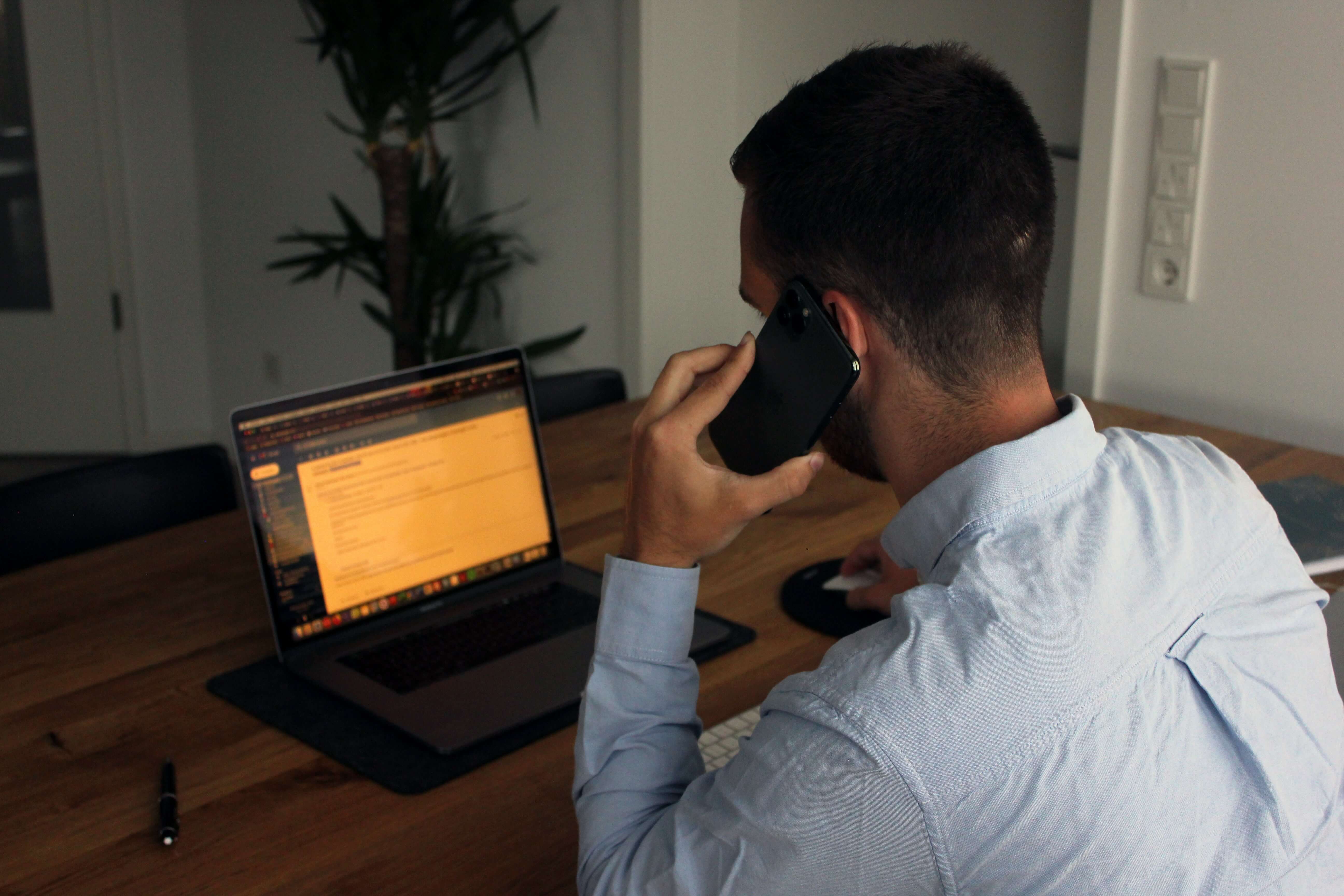 A man sits at his laptop and calls someone to get help with the lien on his home.